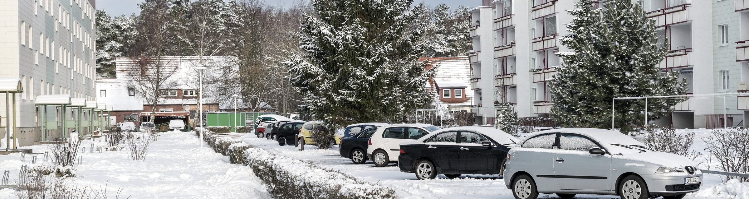 Deux immeubles à logements de part et d'autre de leur stationnement, voitures ensevelies sous la neige