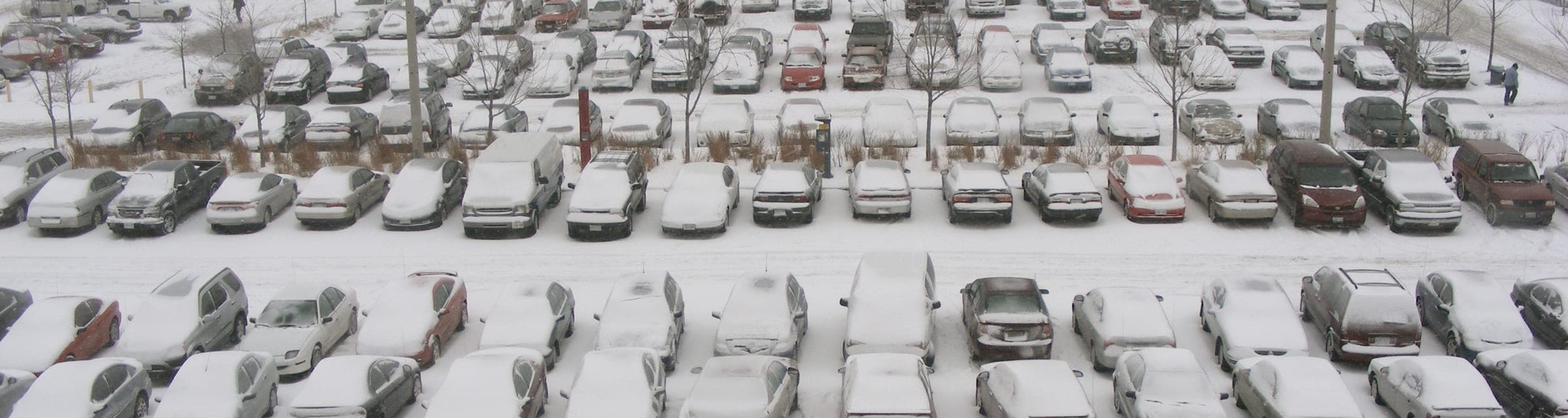 Stationnement d'entreprise enseveli, ses rangées de voitures sous la neige après une tempête